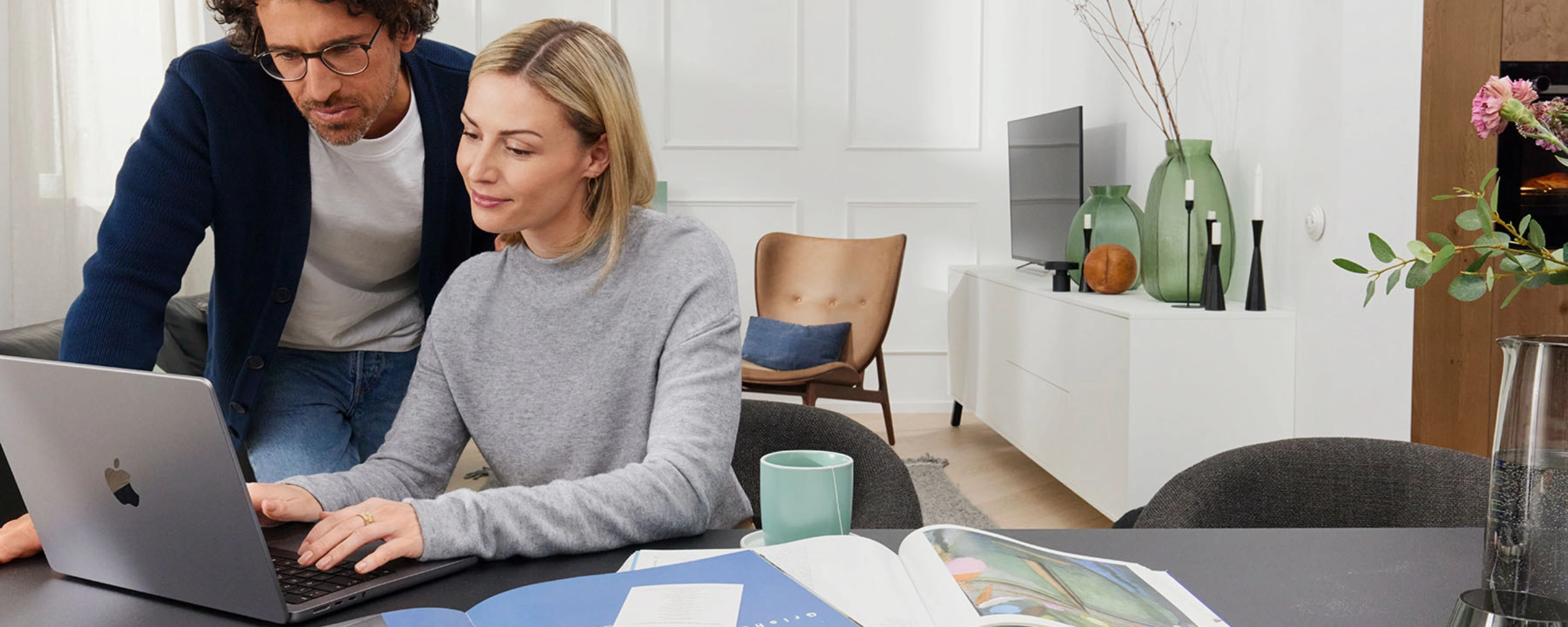 Пара работает вместе за ноутбуком в современной гостиной с Nolte Living.